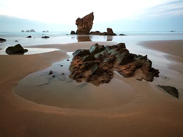 Playa de Aguilar, en Cudillero (Asturias), con la marea baja y el horizonte del mar abierto hacia el oeste